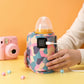 Colorful camouflage-patterned baby bottle warmer with USB cable on a yellow background